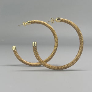 May include: A pair of gold hoop earrings with a woven texture.
