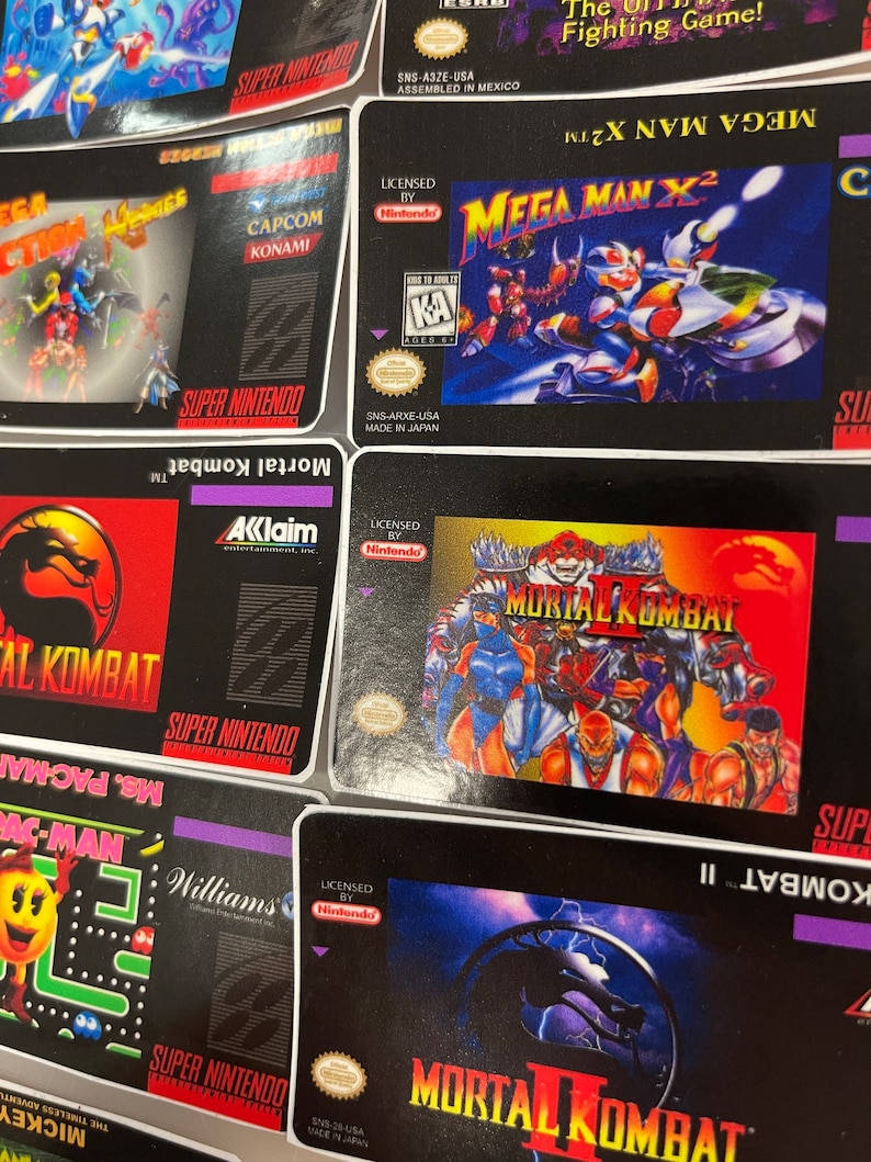 K&ouml;nnte beinhalten: Eine Sammlung von Super Nintendo-Spielkassetten mit Titeln wie "Mortal Kombat", "Mega Man X2" und "Ms. Pac-Man". Die Spielboxen haben farbenfrohe Grafiken und das Super Nintendo-Logo. Die Spiele sind von Nintendo lizenziert.