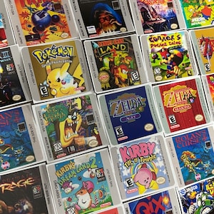 K&ouml;nnte beinhalten: Eine Sammlung bunter Game Boy-Spielekartuschen-Etiketten. Die Etiketten zeigen verschiedene Spieltitel, darunter "Pok&eacute;mon Special Pikachu Edition", "The Legend of Zelda: Oracle of Ages", "Kirby Tilt 'n' Tumble" und "Mega Man".