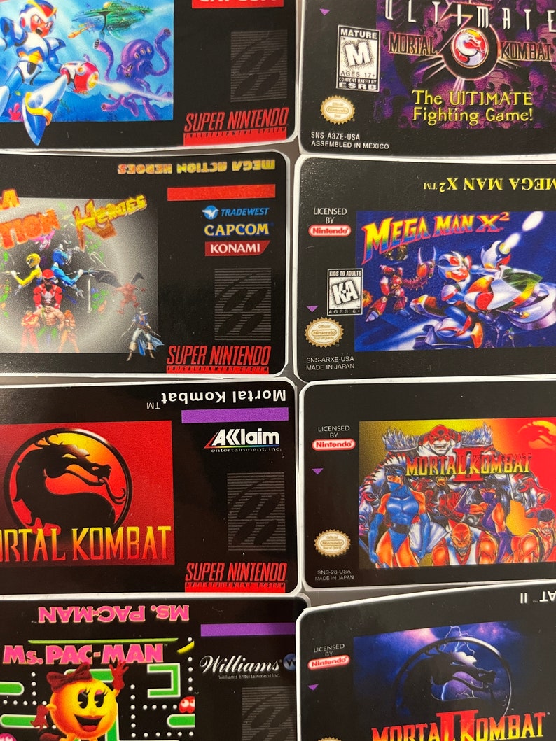 K&ouml;nnte beinhalten: Eine Sammlung von Super Nintendo-Spielkassetten. Zu den Titeln geh&ouml;ren "Mega Man X2", "Mortal Kombat", "Ultimate Mortal Kombat" und "Mega Action Heroes". Die Kassetten zeigen farbenfrohe Spielgrafiken und Logos.