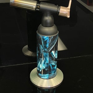 May include: A black and silver torch with a blue and black patterned design. The torch has a long, silver nozzle and a black handle.