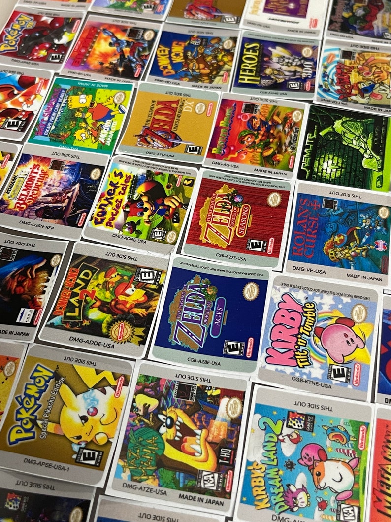 K&ouml;nnte beinhalten: Eine Sammlung von bunten Game Boy-Spielekartuschen-Etiketten mit beliebten Titeln wie Zelda, Donkey Kong, Pokemon, Kirby und mehr. Die Etiketten sind auf wei&szlig;em Papier mit schwarzem Text und Grafiken gedruckt.