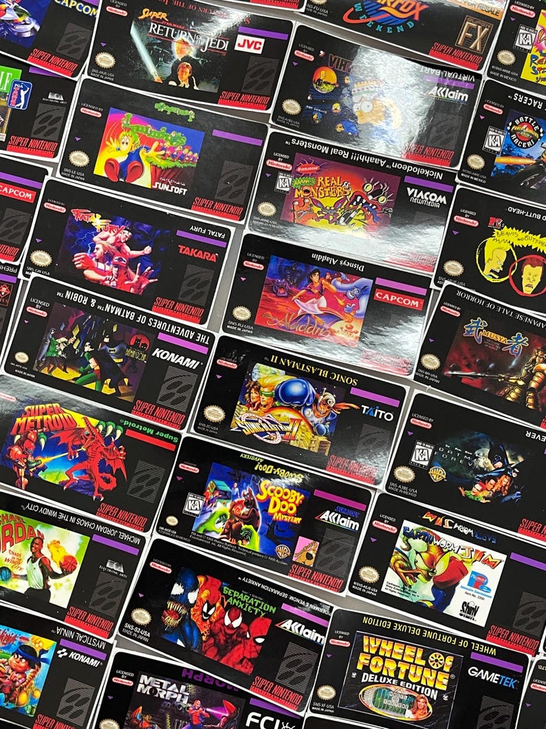 K&ouml;nnte beinhalten: Eine Sammlung von Super Nintendo-Spielkassetten mit verschiedenen Titeln und farbenfrohen Cover-Art. Zu den Spielen geh&ouml;ren "Super Metroid", "Aladdin", "Sonic Blastman II" und "Wheel of Fortune Deluxe Edition". Die Kassetten sind schwarz mit lila und wei&szlig;em Text.