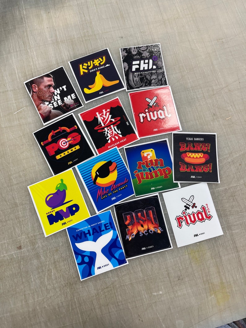 K&ouml;nnte beinhalten: Eine Sammlung von 12 bunten Aufklebern mit verschiedenen Designs, darunter eine Banane, ein Videospielcharakter, ein Wal und ein Basketballspieler. Die Aufkleber sind alle quadratisch und haben einen wei&szlig;en Rand. Der Text auf den Aufklebern lautet "Drift King", "Nuclear Heat", "Life of the Party", "Bang!" und "Rival".