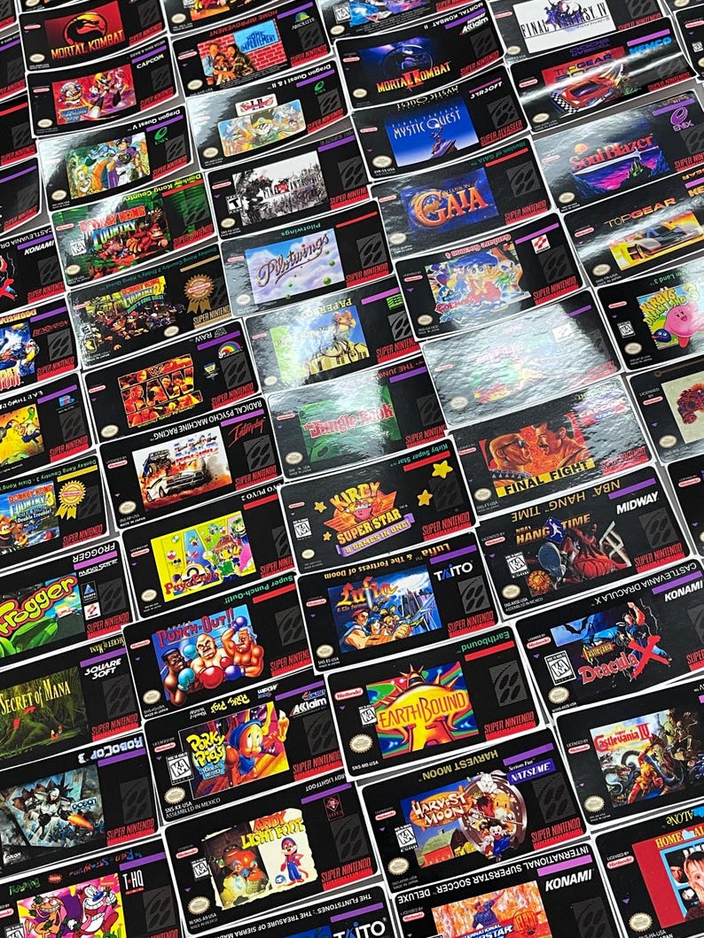 K&ouml;nnte beinhalten: Eine Sammlung von Super Nintendo Entertainment System (SNES) Spielkassetten. Die Kassetten zeigen farbenfrohe Spielbox-Art mit Titeln wie "Mortal Kombat" und "Earthbound". Die Spiele sind auf einer reflektierenden Oberfl&auml;che angeordnet.