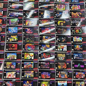 K&ouml;nnte beinhalten: Eine Sammlung von Retro-Super-Nintendo-Spielkassetten. Die Kassetten zeigen farbenfrohe Spielgrafiken und -titel, darunter "Mortal Kombat", "Street Fighter" und "NHL Hockey". Die Kassetten sind eng aneinandergereiht und bilden ein gitterartiges Muster.