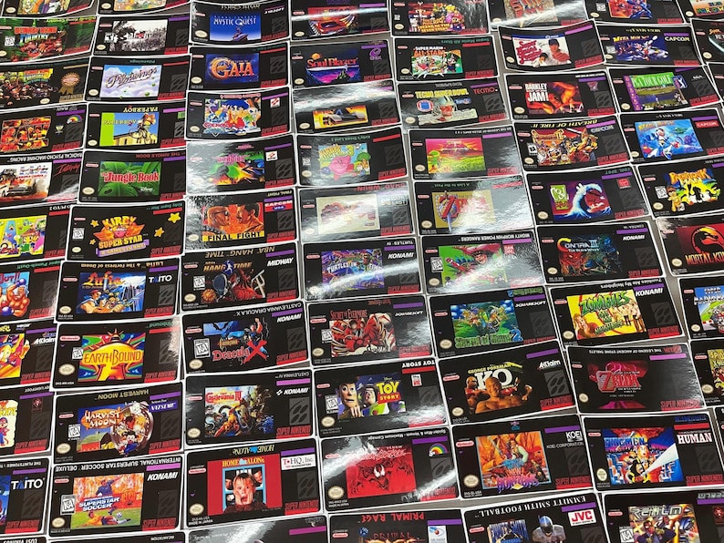 K&ouml;nnte beinhalten: Eine Sammlung von Super Nintendo Entertainment System (SNES) Spielkassetten. Die Kassetten zeigen farbenfrohe Spielbox-Artworks und Titel wie "Kirby Super Star", "Earthbound" und "Final Fight". Die Spiele sind eng angeordnet.