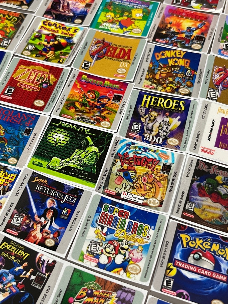 K&ouml;nnte beinhalten: Eine Sammlung von bunten Spielkassetten-Etiketten f&uuml;r Game Boy und Game Boy Color. Die Etiketten zeigen verschiedene beliebte Videospieltitel, darunter Zelda, Donkey Kong, Super Mario Bros., Pokemon und Star Wars: Die R&uuml;ckkehr der Jedi.