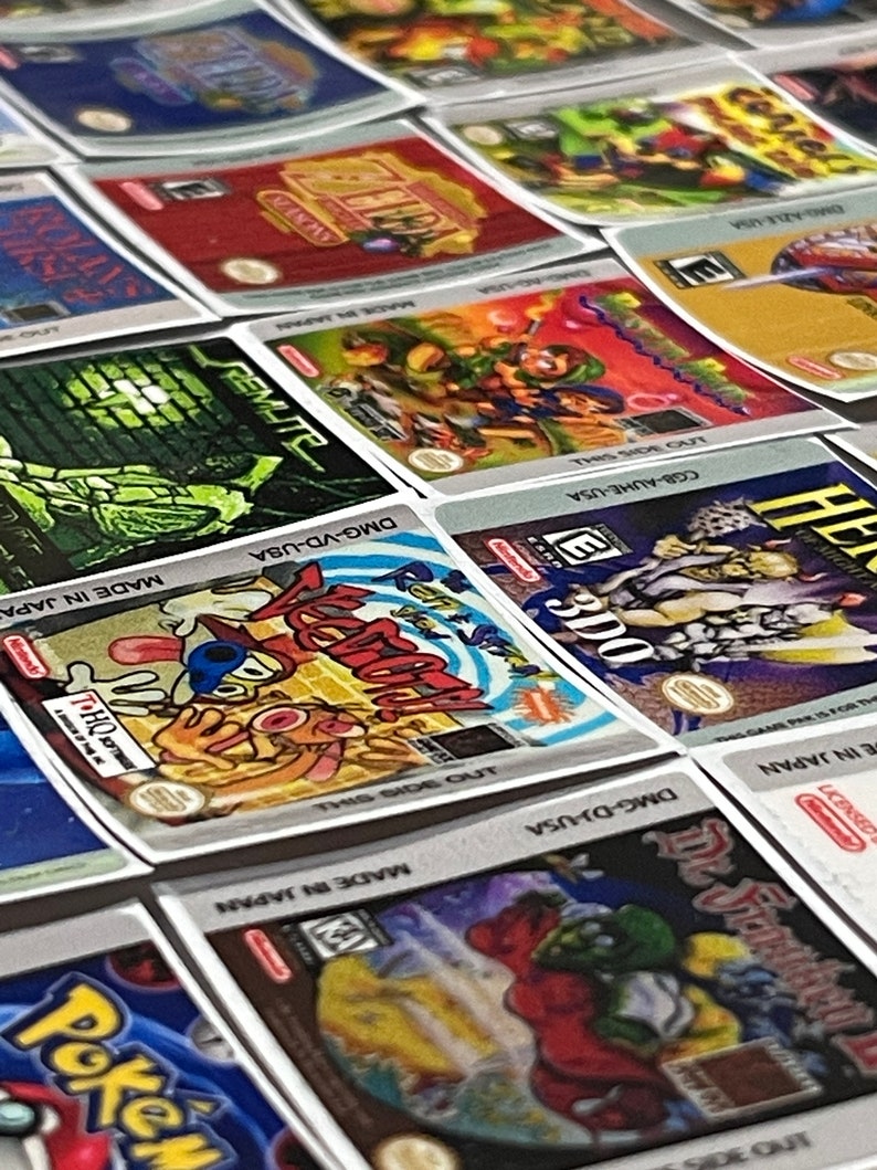 K&ouml;nnte beinhalten: Eine Sammlung von bunten Nintendo Game Boy Advance-Spielkassetten. Die Kassetten sind in einem Raster angeordnet und zeigen verschiedene Spieltitel, darunter "Pok&eacute;mon", "Kirby's Dream Land" und "The Legend of Zelda".