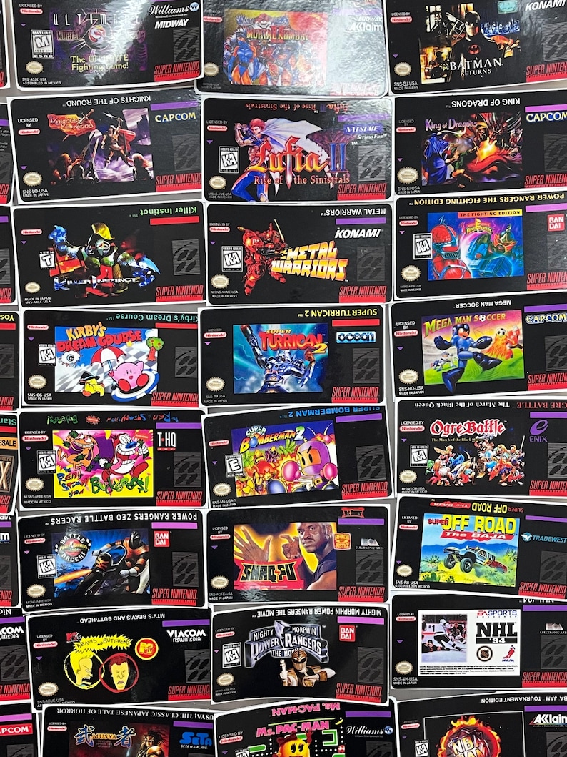 K&ouml;nnte beinhalten: Eine Sammlung von Super Nintendo-Spielkassetten mit verschiedenen Titeln und farbenfrohen Box-Art. Zu den Spielen geh&ouml;ren "Kirby's Dream Course", "Batman Returns" und "Mighty Morphin Power Rangers". Die Kassetten sind auf einer schwarzen Oberfl&auml;che angeordnet.