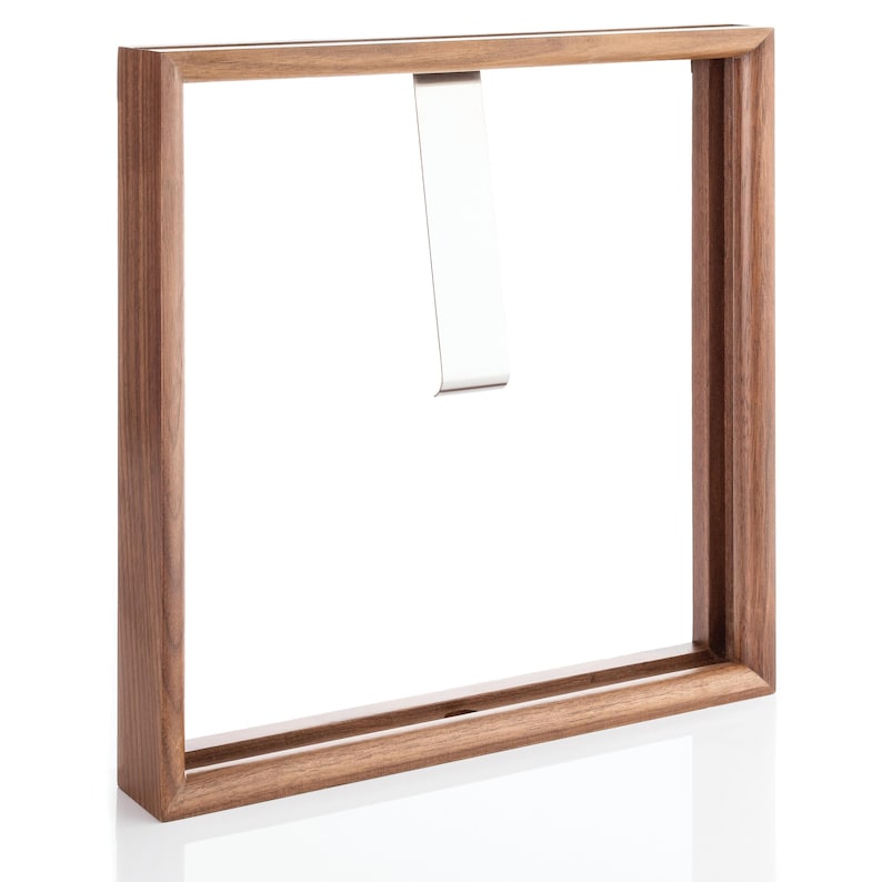 Op de afbeelding: Een houten fotolijst met een metalen hanger. De lijst is gemaakt van donker hout en heeft een eenvoudig ontwerp.