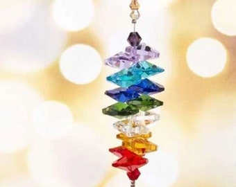 May include: A hanging crystal suncatcher with a rainbow of faceted crystal accents. The suncatcher features a clear, faceted crystal ball at the bottom and a gold-colored chain at the top. The crystals are arranged in a vertical line.