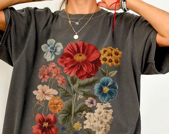 May include: A dark gray oversized t-shirt with a floral print featuring red, blue, yellow, and white flowers. The flowers are arranged in a bouquet and have a vintage style.