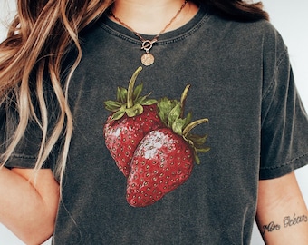 May include: A charcoal grey short-sleeve t-shirt featuring a graphic illustration of two red strawberries with green leaves centered on the chest. The fabric has a washed, vintage-style texture. The word Pepper is printed in black on a yellow circle.