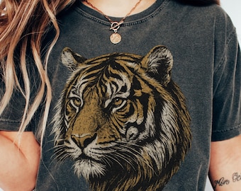 May include: A dark gray t-shirt with a vintage-style illustration of a tiger's face. The tiger has brown and gold stripes and a black nose.