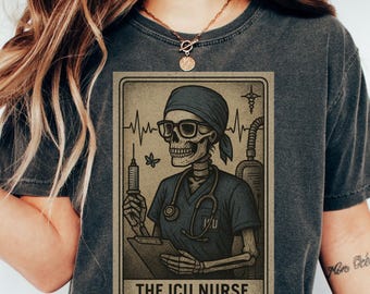 May include: Dark gray t-shirt featuring a vintage-style illustration of a skeleton in scrubs, glasses, and a headscarf, holding a syringe and clipboard. The text "THE ICU NURSE" is displayed below the image. The shirt has a crew neck.