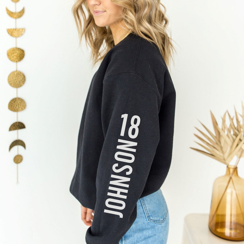 May include: Black sweatshirt with the text "JOHNSON 18" printed vertically on the left sleeve.