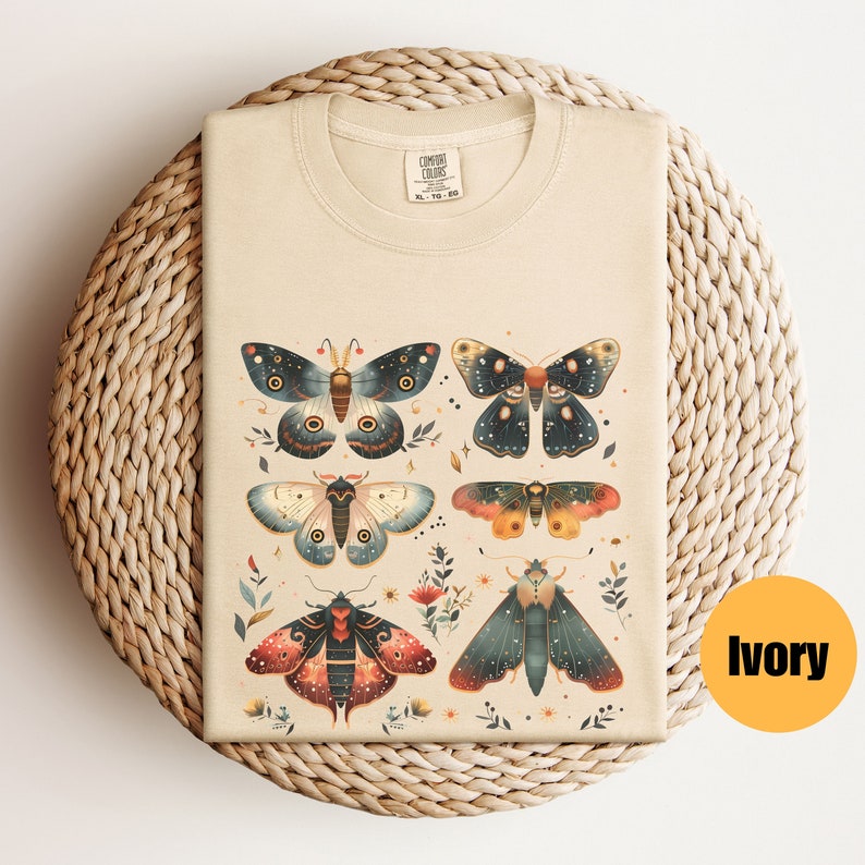 Puede incluir: Una camiseta beige con un estampado de seis polillas coloridas con detalles intrincados. Las polillas est&aacute;n rodeadas de peque&ntilde;as flores y hojas. La camiseta est&aacute; hecha de un material suave y c&oacute;modo, perfecta para el uso diario.