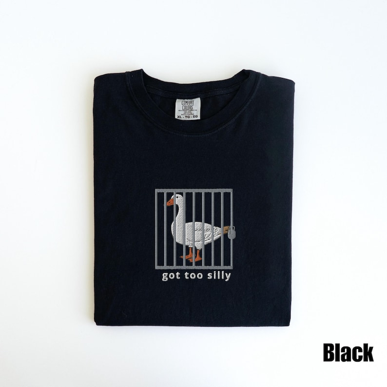 May include: Black t-shirt featuring a white goose inside a gray cage with the text "got too silly" below the cage. The goose has orange feet and a gray beak. The shirt has a Comfort Colors tag.