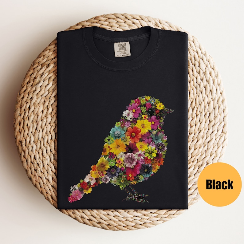 May include: Black t-shirt with a colorful bird design made of flowers. The bird is facing right and has a long tail. The shirt is made of a soft, comfortable material.