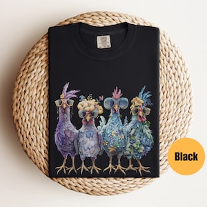 Peut inclure: T-shirt noir avec un motif de quatre poulets portant des lunettes de soleil et des bandeaux floraux. Les poulets sont debout en rang et regardent le spectateur.