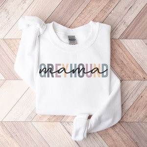 May include: White sweatshirt with the text "Greyhound mama" in rainbow colors.
