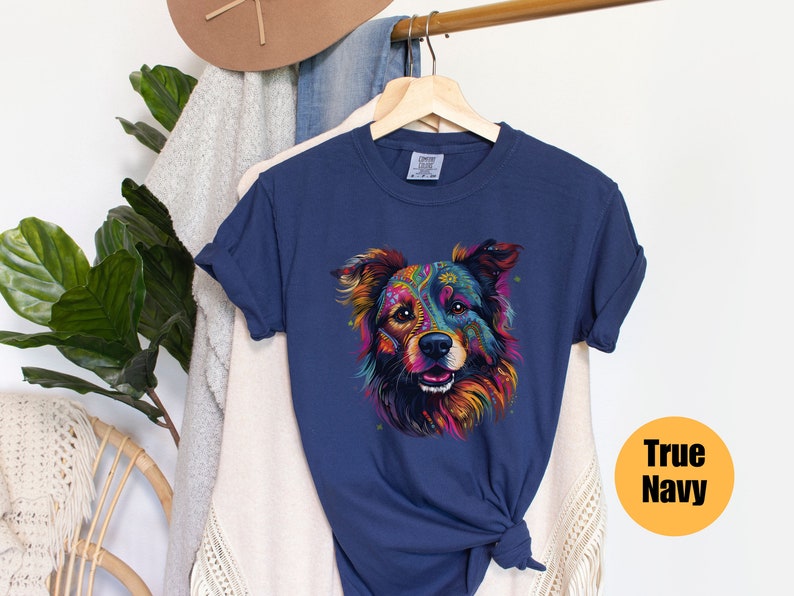 May include: A navy blue t-shirt featuring a colourful, psychedelic dog illustration. The dog has a black nose and brown eyes. The text "True Navy" is in a yellow circle on the right side of the image.
