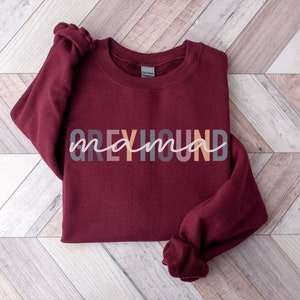 May include: A maroon sweatshirt with the text "Greyhound mama" in colorful letters.