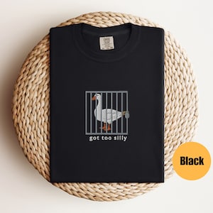 May include: Black t-shirt with a white goose in a cage and the text "got too silly".