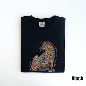 May include: Black t-shirt with a floral cat design. The cat is made up of colorful flowers and is sitting in a relaxed pose. The shirt has a crew neck and short sleeves.