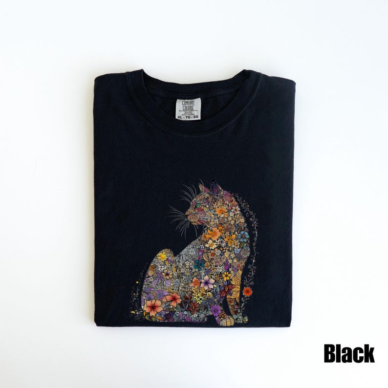May include: Black t-shirt with a floral cat design. The cat is made up of colorful flowers and is sitting in a relaxed pose. The shirt has a crew neck and short sleeves.
