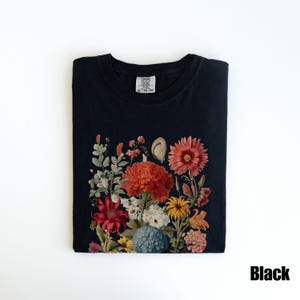 Pu&ograve; includere: Maglietta nera con stampa floreale che presenta una variet&agrave; di fiori in tonalit&agrave; di rosso, arancione, giallo e rosa. I fiori sono disposti a forma di bouquet e sono circondati da foglie verdi. La maglietta ha un collo rotondo e maniche corte.