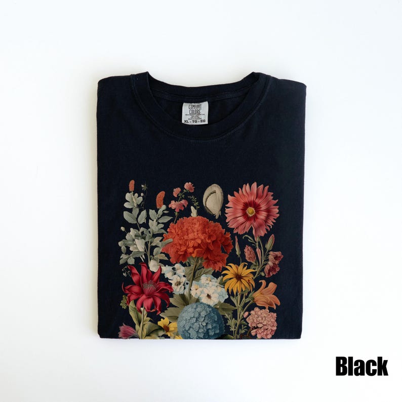 Pu&ograve; includere: Maglietta nera con stampa floreale che presenta una variet&agrave; di fiori in tonalit&agrave; di rosso, arancione, giallo e rosa. I fiori sono disposti a forma di bouquet e sono circondati da foglie verdi. La maglietta ha un collo rotondo e maniche corte.