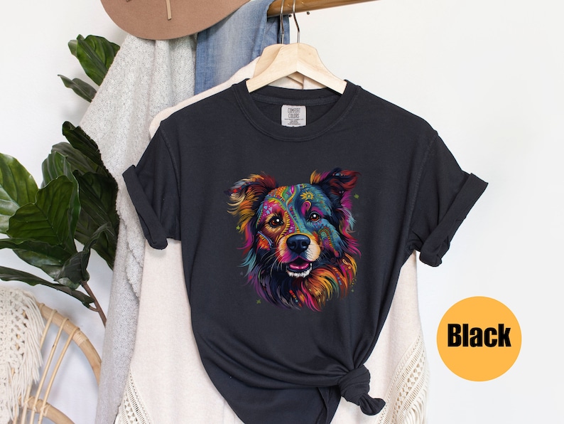 May include: A black t-shirt featuring a colourful graphic of a dog's face. The dog has a black, brown and white coat with colourful patterns on its fur. The dog is looking directly at the viewer.