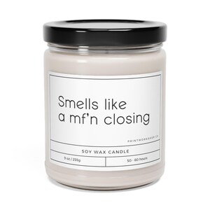 May include: A beige glass candle jar with a black lid. The label reads "Smells like a mf'n closing" and "Soy Wax Candle". The candle is 9 oz / 255g and has a burn time of 50-60 hours.
