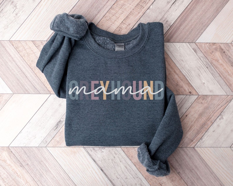May include: A dark gray sweatshirt with the text "Greyhound mama" in colorful letters. The letters are in a variety of pastel colors, including pink, yellow, and blue.