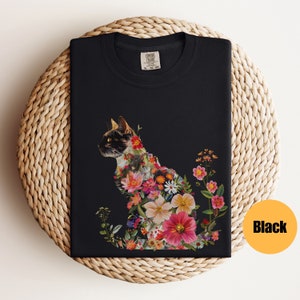 May include: Black t-shirt featuring a floral cat design. The cat is made up of colourful flowers and leaves. The shirt is a comfortable fit and is perfect for everyday wear.