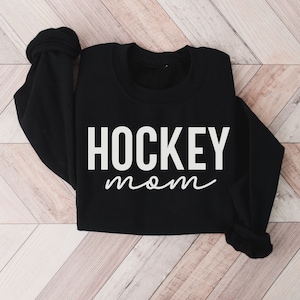 May include: Black sweatshirt with white text that reads "HOCKEY mom" in a cursive font.