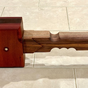 May include: A wooden mallet with a red and brown head and a walnut handle. The handle has a unique design with cutouts.