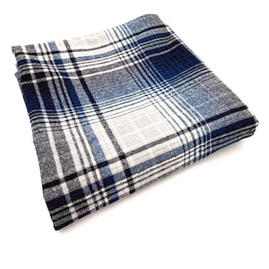 May include: A folded textile featuring a plaid pattern in shades of navy blue, black, white, and light gray. The fabric displays a woven texture with intersecting horizontal and vertical lines forming a classic checkered design across the surface.