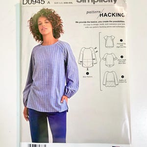 May include: A Simplicity D0945 sewing pattern envelope for a top in sizes XXS-XXL. The front shows a person wearing a blue and white striped long-sleeve top with raglan sleeves and gathered cuffs, alongside diagrams for pattern hacking variations.