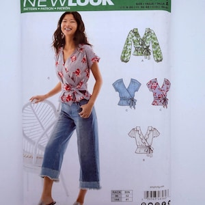 May include: New Look sewing pattern 6560 for a wrap-style top with short or long sleeves. The envelope features a photograph of a person wearing a floral print wrap top with blue jeans, alongside technical illustrations of three variations.