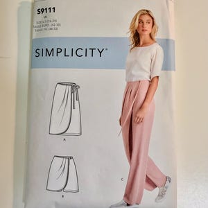 May include: A Simplicity sewing pattern envelope S9111 for sizes U.S. 16-24. The front displays a white top and pink wrap-style trousers, along with line drawings of a wrap skirt labelled A and a shorter wrap skirt labelled B. The text S9111 is visible.