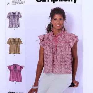 May include: Simplicity sewing pattern R11451 for a blouse with a ruffled collar, flutter sleeves, and a front tie closure. The pattern envelope displays three variations of the top in floral, plaid, and solid pink prints with U.S. sizes 4-16.