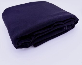 May include: A folded piece of dark navy blue fabric with a matte texture. The textile is layered in multiple neat folds, showing a consistent deep blue color throughout the material. The edges of the fabric are visible along the side of the stack.
