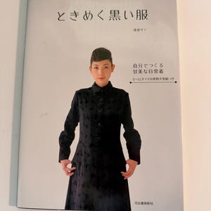 Puede incluir: Portada de libro con una mujer con un abrigo negro estampado. El título está en caracteres japoneses, con texto japonés adicional. El libro se titula "Tokimeku Kuroi Fuku" e incluye texto sobre cómo hacer ropa hermosa para todos los días.