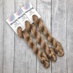 May include: Three skeins of hand-dyed 100% cotton yarn in the color Desert Camel. Each skein is 50 yards long. The yarn is labeled "StitchyStuff".