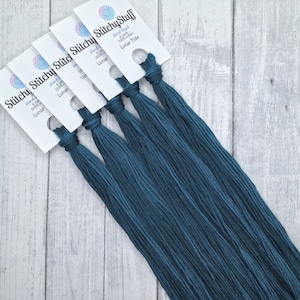 May include: Five skeins of teal blue embroidery floss, each labeled "Stitchy Stitchy Stuff" with the text "Hand-Dyed 8 yards 100% cotton Lunar Tide".