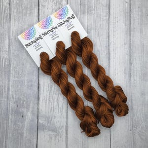 May include: Three skeins of brown hand-dyed 100% cotton yarn labeled "StitchysStuff Hand Dyed 100% cotton Nutmeg"