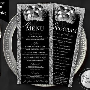 May include: Black and silver event menu and program cards with a balloon graphic. The menu lists starters, main courses, desserts, and drinks. The program outlines the order of events. The cards are on a silver-rimmed plate with silverware.